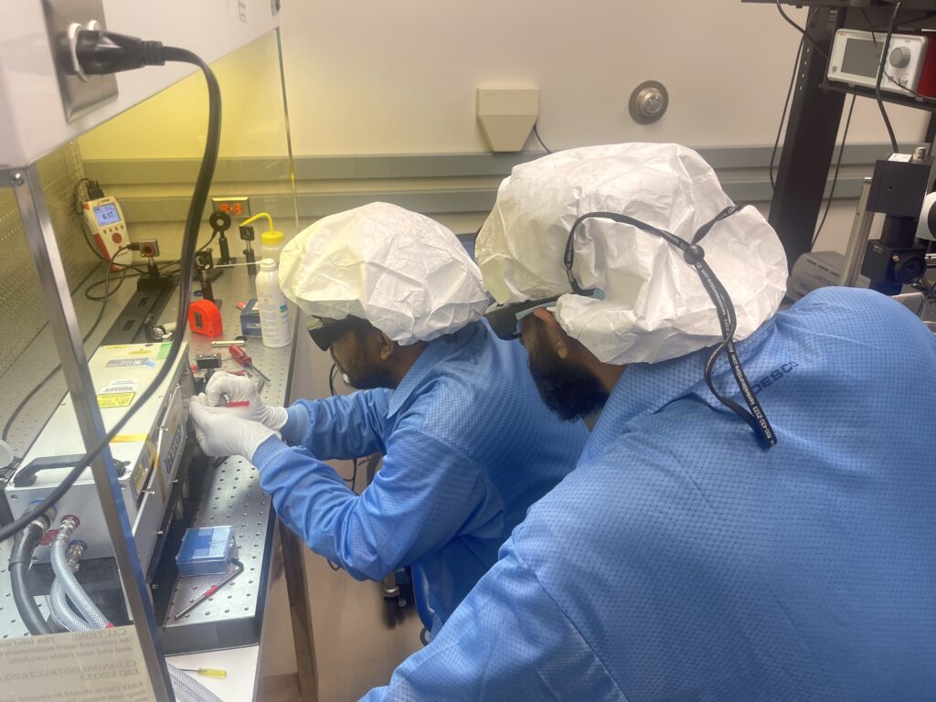 Two lidar lab personnel work at a clean bench on a laser.